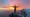Man standing triumphantly on mountain peak with outstretched arms, expressing victory and freedom.