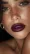 Close-up of a woman with bold purple lipstick, blurred background emphasizing lip detail.